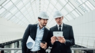 two-successful-entrepreneur-helmet-with-project-laptop-new-buildings-stay-near-glass-roof_496169-971